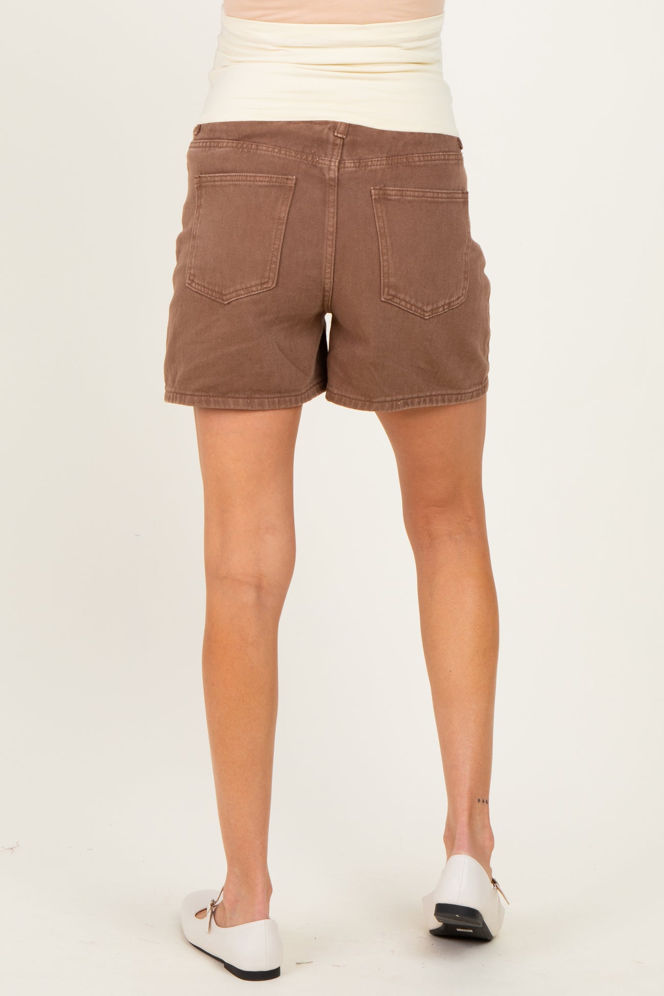 woman wearing brown maternity shorts, showing a view from the back, no baby bump visible