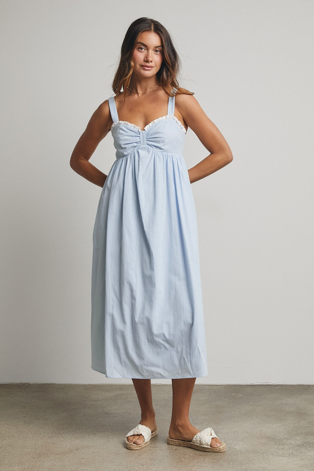 woman wearing a light blue midi dress with a ruching detail and spaghetti straps
