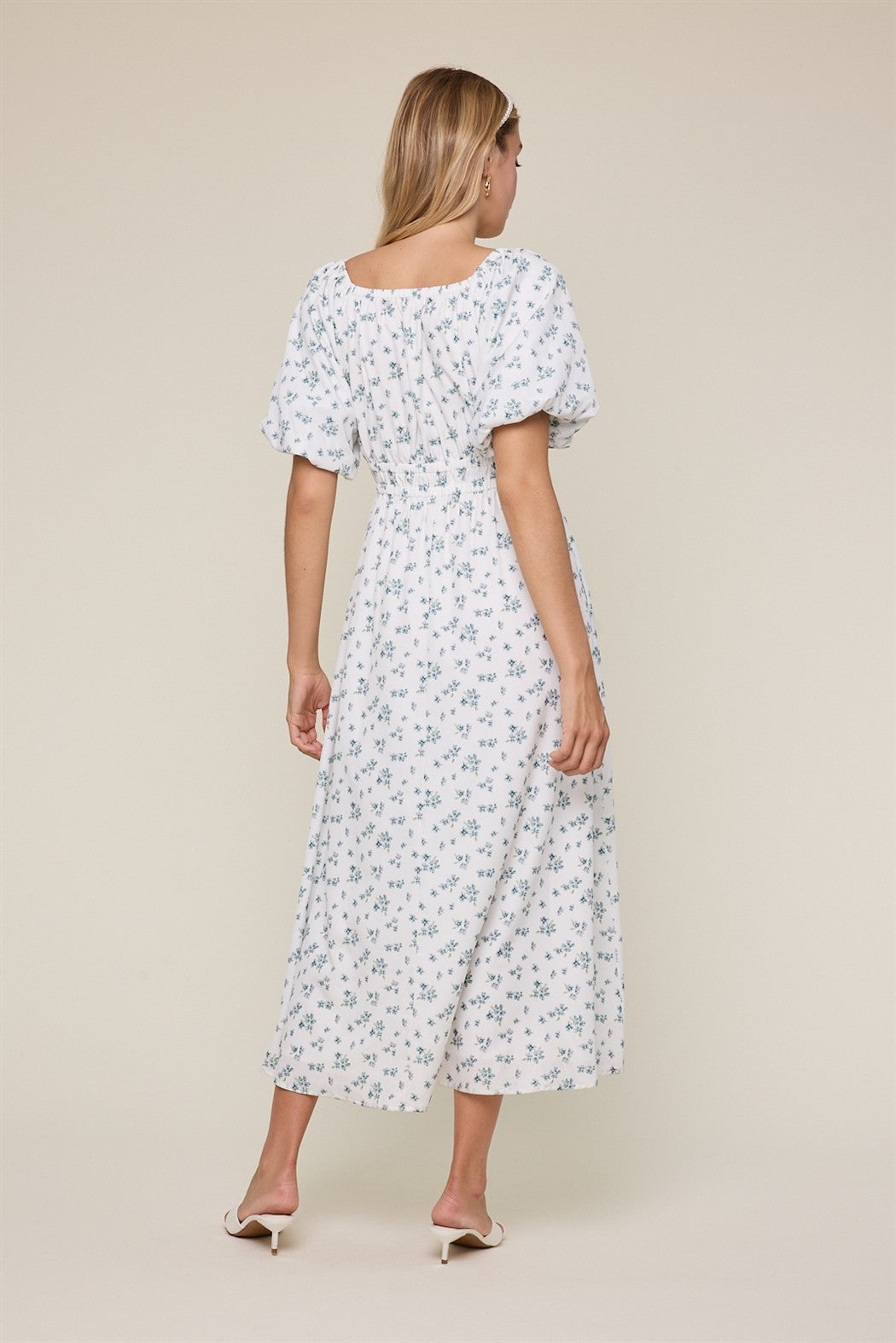 woman wearing a white floral maxi dress with puff sleeves, shown from the back