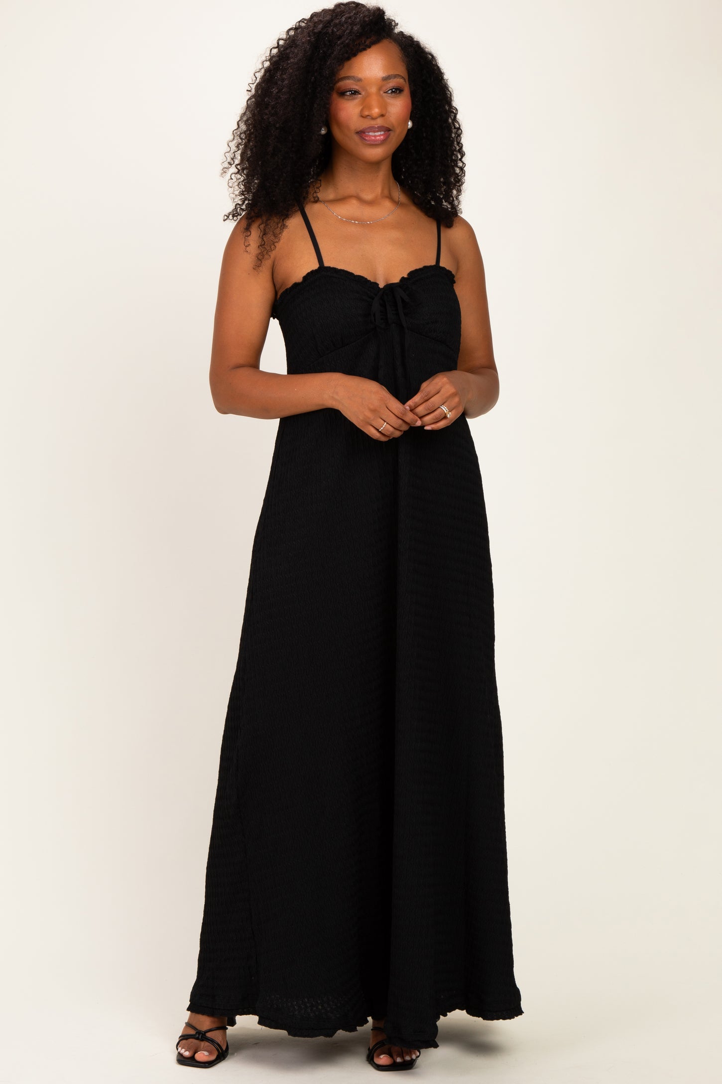 woman wearing a black maxi dress with a knotted bandeau style and spaghetti straps
