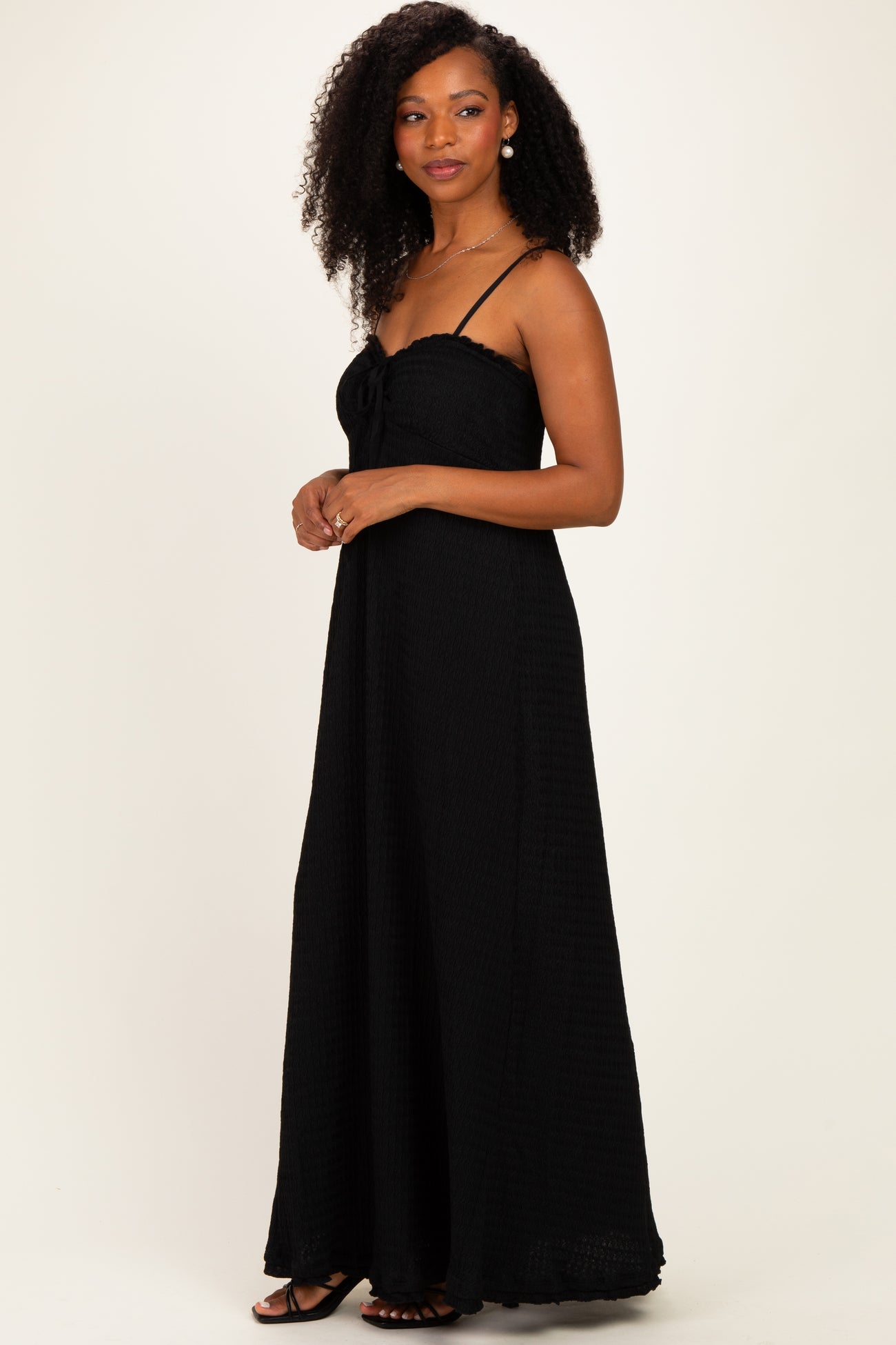 woman wearing a black long maxi dress with spaghetti straps and a tie front detail