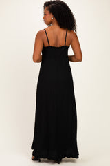 woman wearing a black maxi dress with spaghetti straps and a textured design, showing the back view