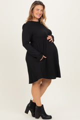 woman wearing a black long sleeve maternity dress with pockets and a visible baby bump