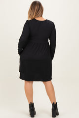 woman wearing a black long sleeve maternity dress with a fitted bodice and loose skirt, showing a baby bump from behind