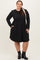 woman wearing a black long sleeve plus size dress with a flared skirt and pockets, styled with ankle boots