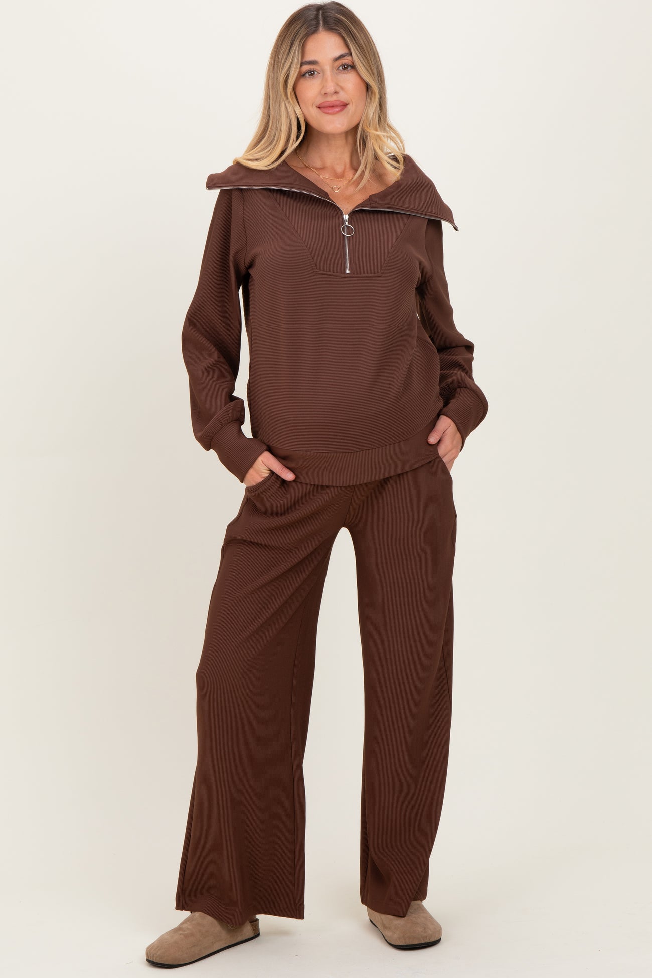 woman wearing a brown maternity loungewear set with a zip-up top and wide-leg pants, featuring a relaxed fit