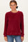 woman wearing a burgundy fuzzy long sleeve sweater with ribbed texture and relaxed fit, styled with blue jeans