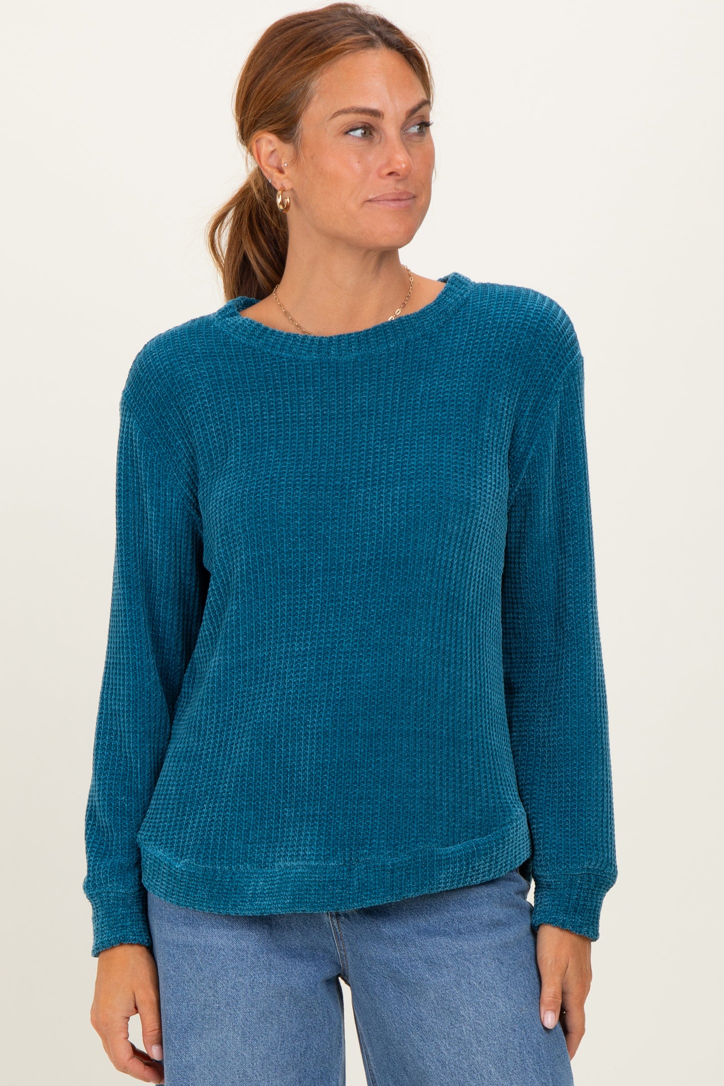 woman wearing a teal long sleeve waffle knit sweater with a relaxed fit and round neckline