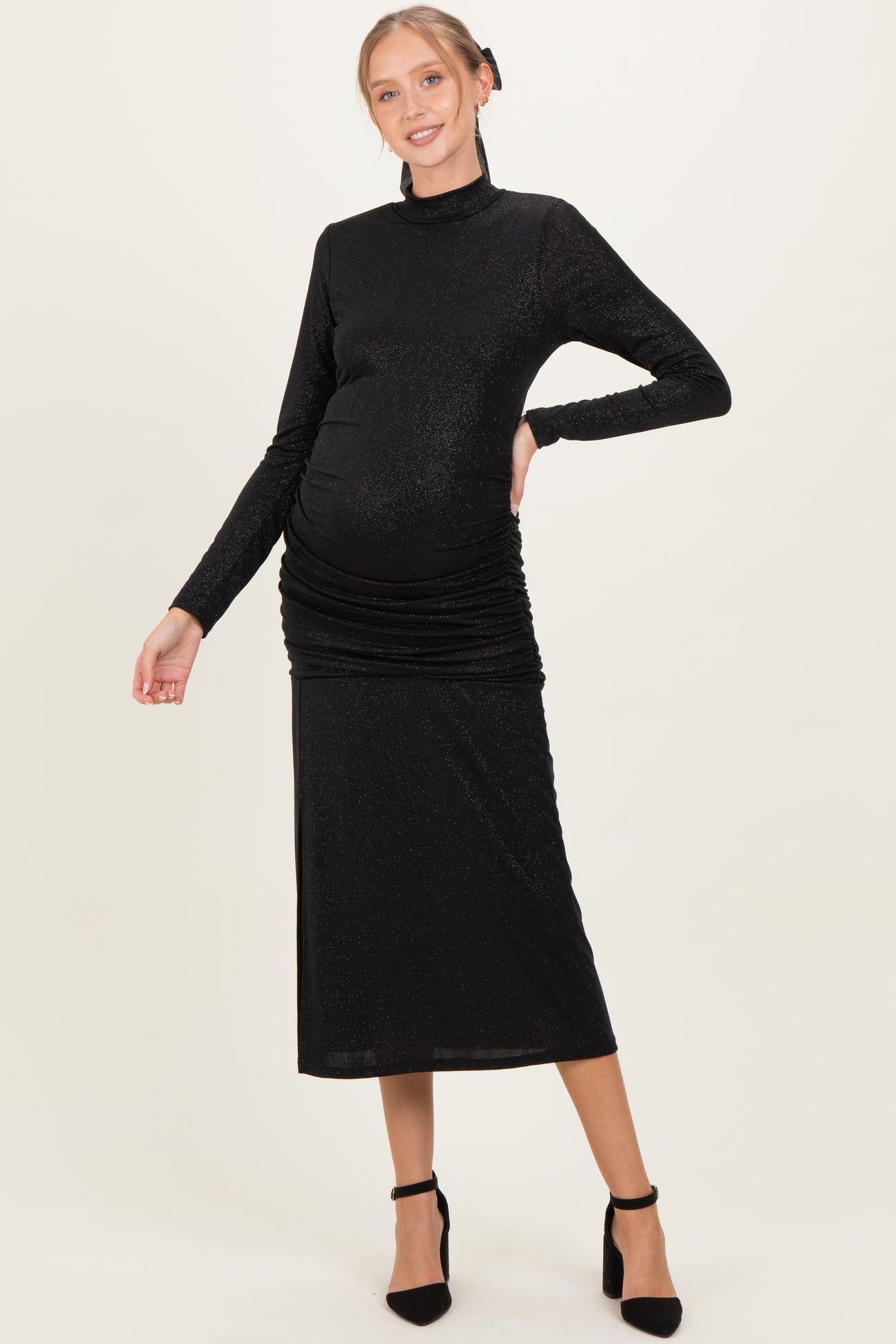 woman wearing a black long sleeve maternity dress with ruching and a visible baby bump