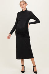 woman wearing a black long sleeve maternity dress with ruching and a visible baby bump