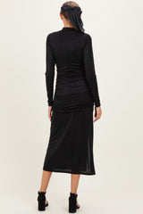 woman wearing a black long sleeve maternity dress with ruched detailing and a midi length, styled with a headscarf
