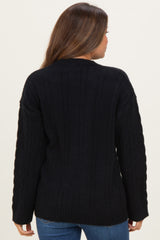 woman wearing a black cable knit maternity sweater, view from the back, showing long sleeves and relaxed fit