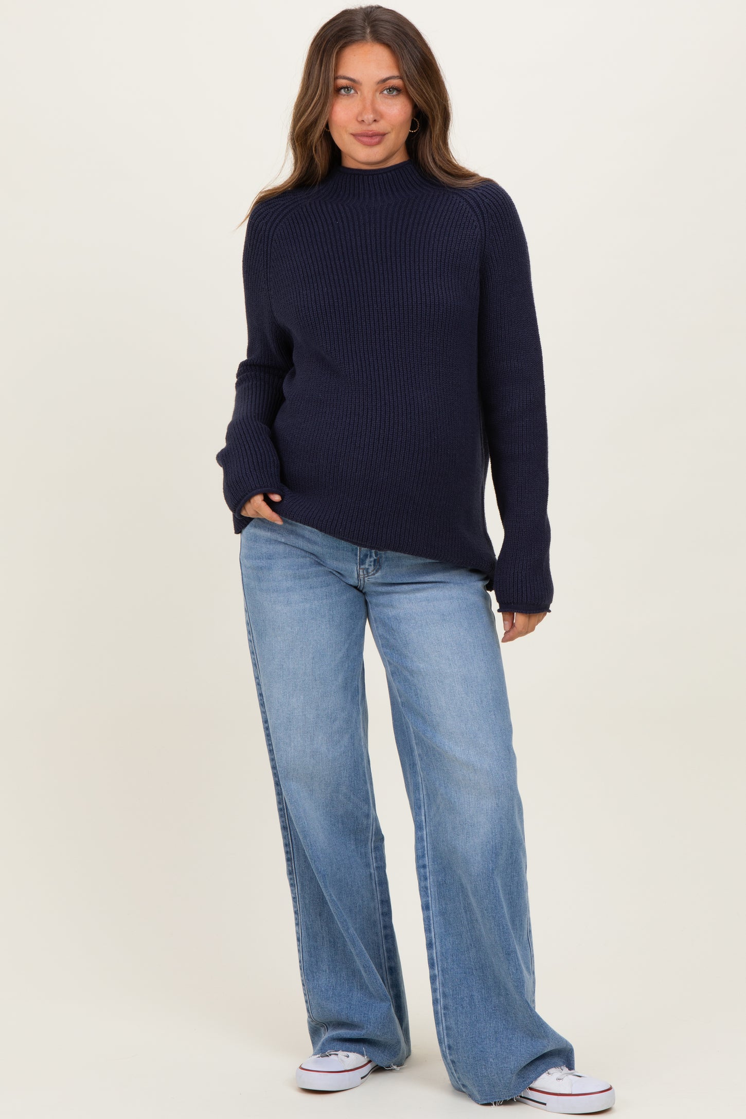woman wearing a dark navy ribbed maternity sweater with a relaxed fit and light blue wide-leg jeans, no baby bump visible