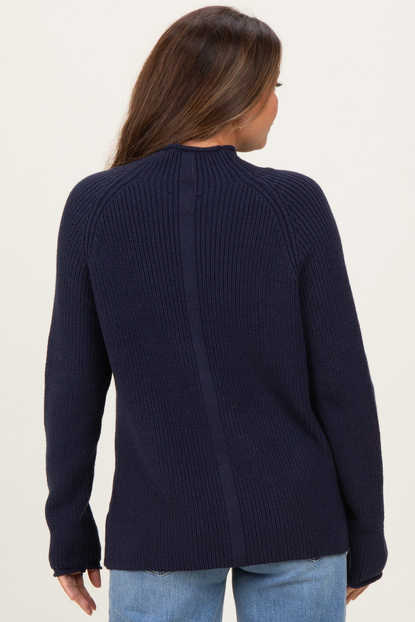 woman wearing a navy blue ribbed maternity sweater, showing the back detail and relaxed fit