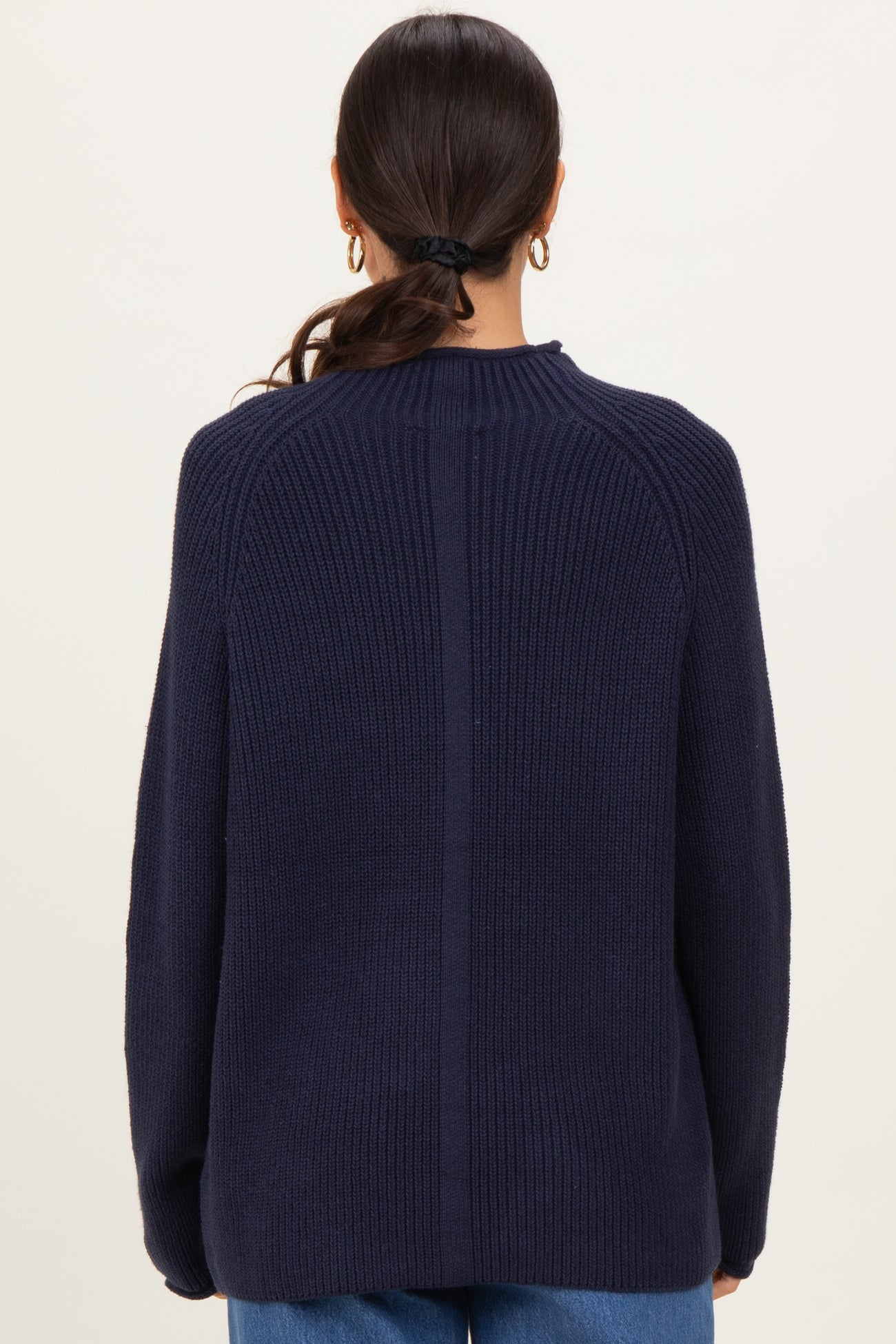 woman wearing a navy blue oversized ribbed sweater, showing the back view with a relaxed fit and dropped shoulders