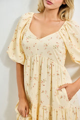 woman wearing a yellow floral puff sleeve dress with a v-neck and tiered skirt