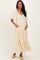 woman wearing a yellow floral maternity maxi dress with short puff sleeves and side pockets, showing her baby bump
