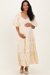 woman wearing a cream floral maternity maxi dress and holding her baby bump