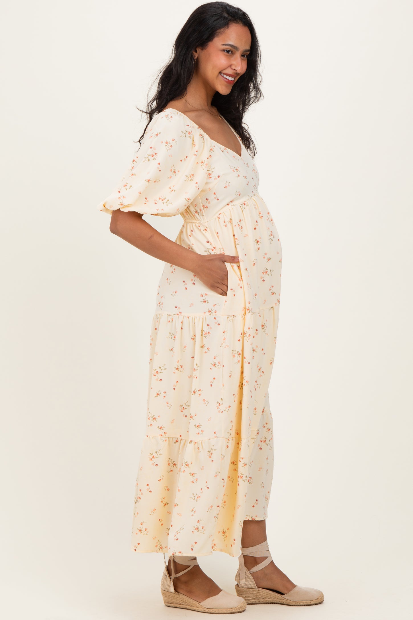 woman wearing a yellow floral maternity dress with short puff sleeves and a visible baby bump