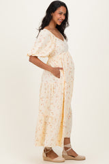 woman wearing a yellow floral maternity dress with short puff sleeves and a visible baby bump