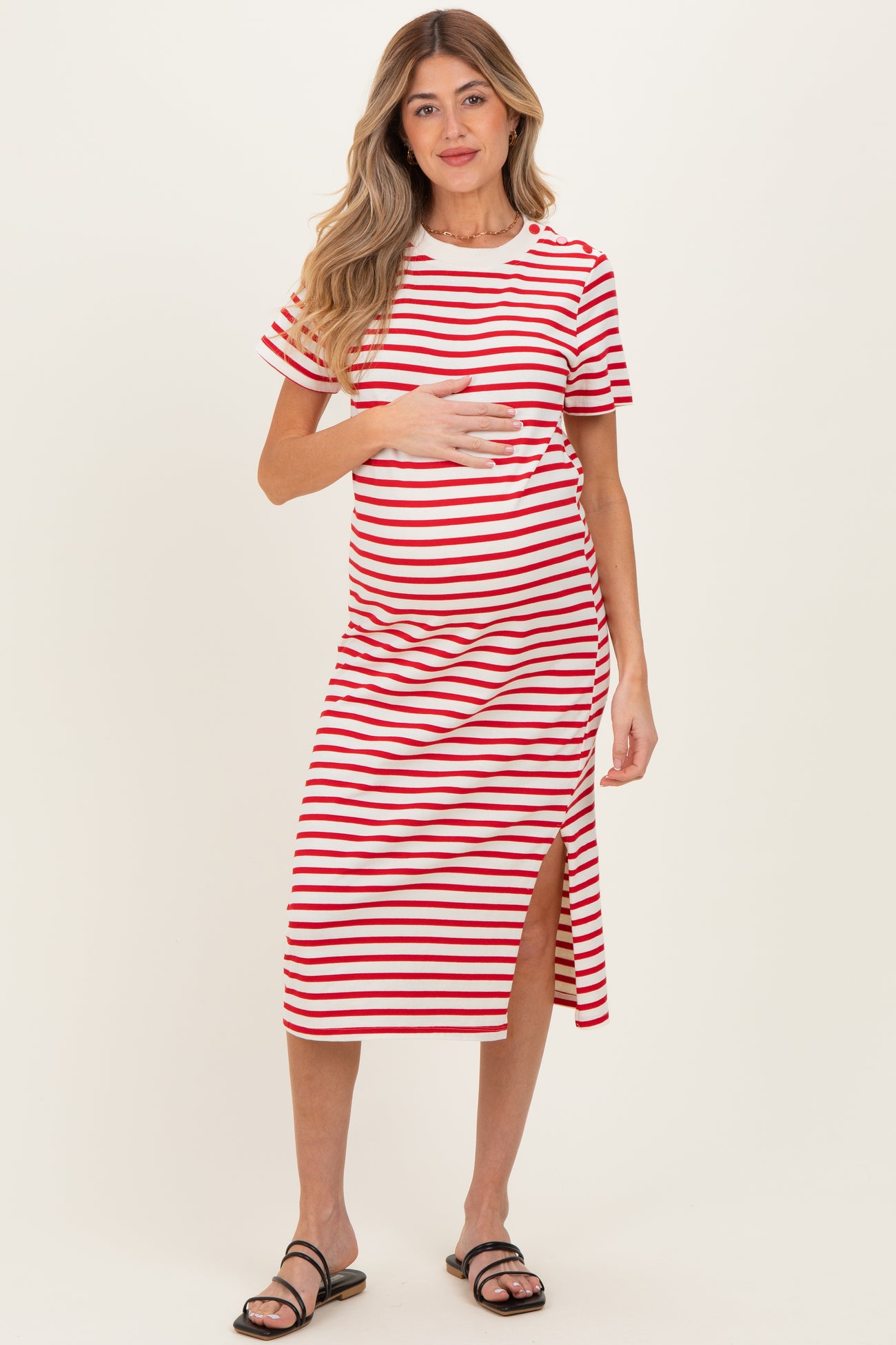 woman wearing a red and white striped maternity dress with a side slit and holding her baby bump
