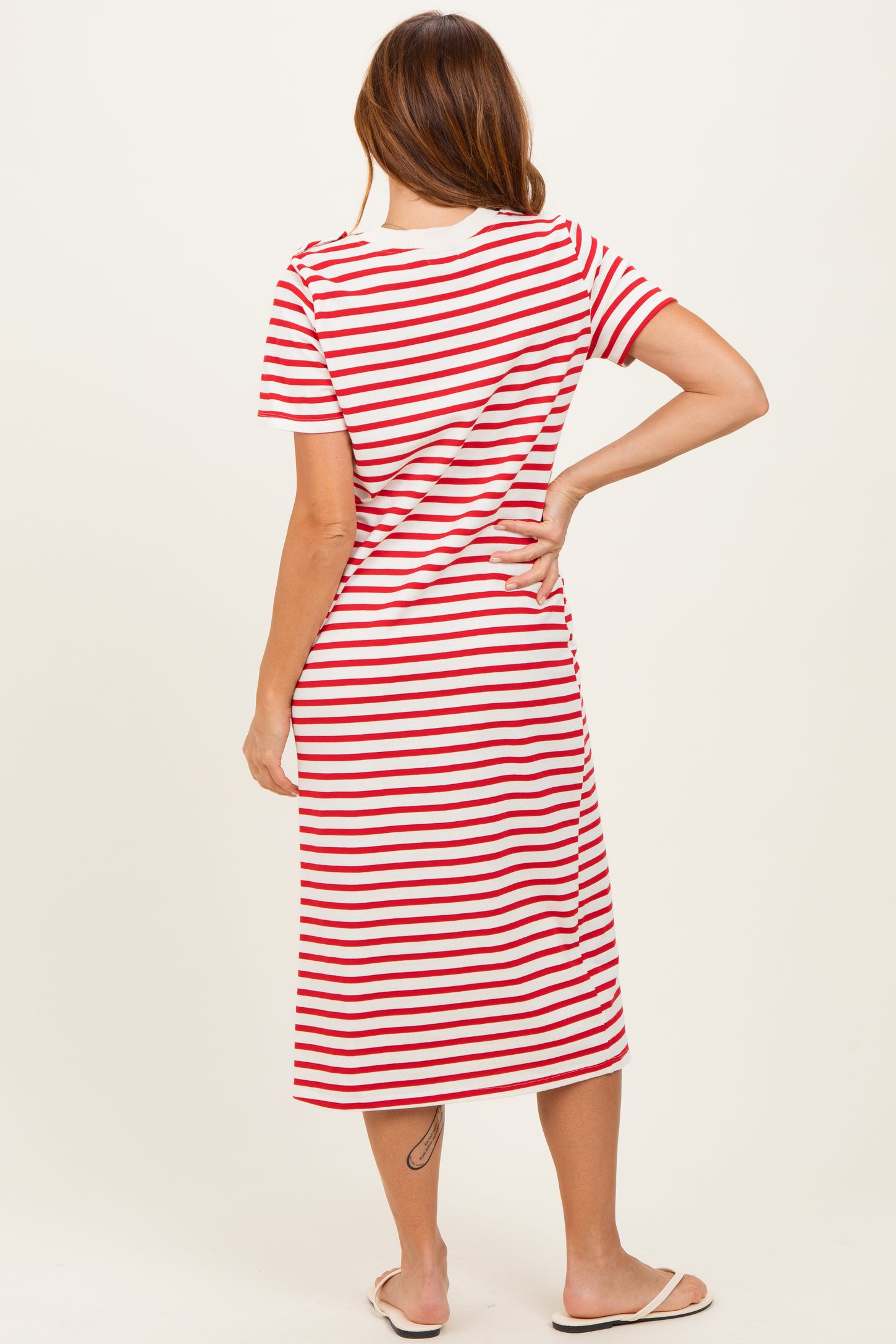 woman wearing a red and white striped midi dress with short sleeves and a relaxed fit, viewed from the back