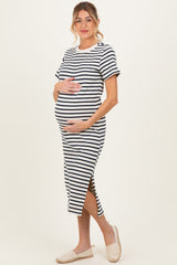 woman wearing a black and white striped maternity dress with side slits and holding her baby bump