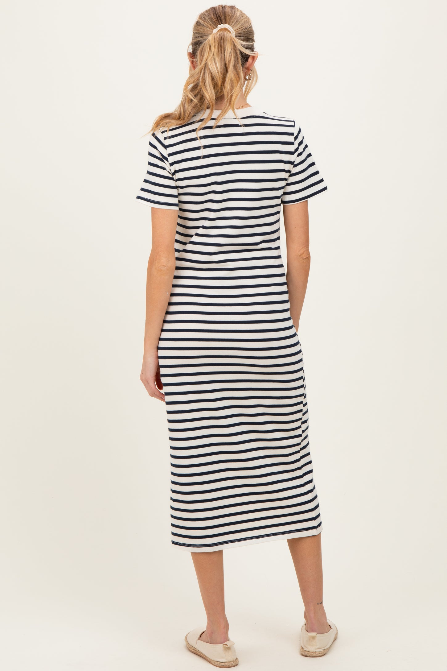 woman wearing a navy and white striped maternity dress with a knee-length cut, view from the back