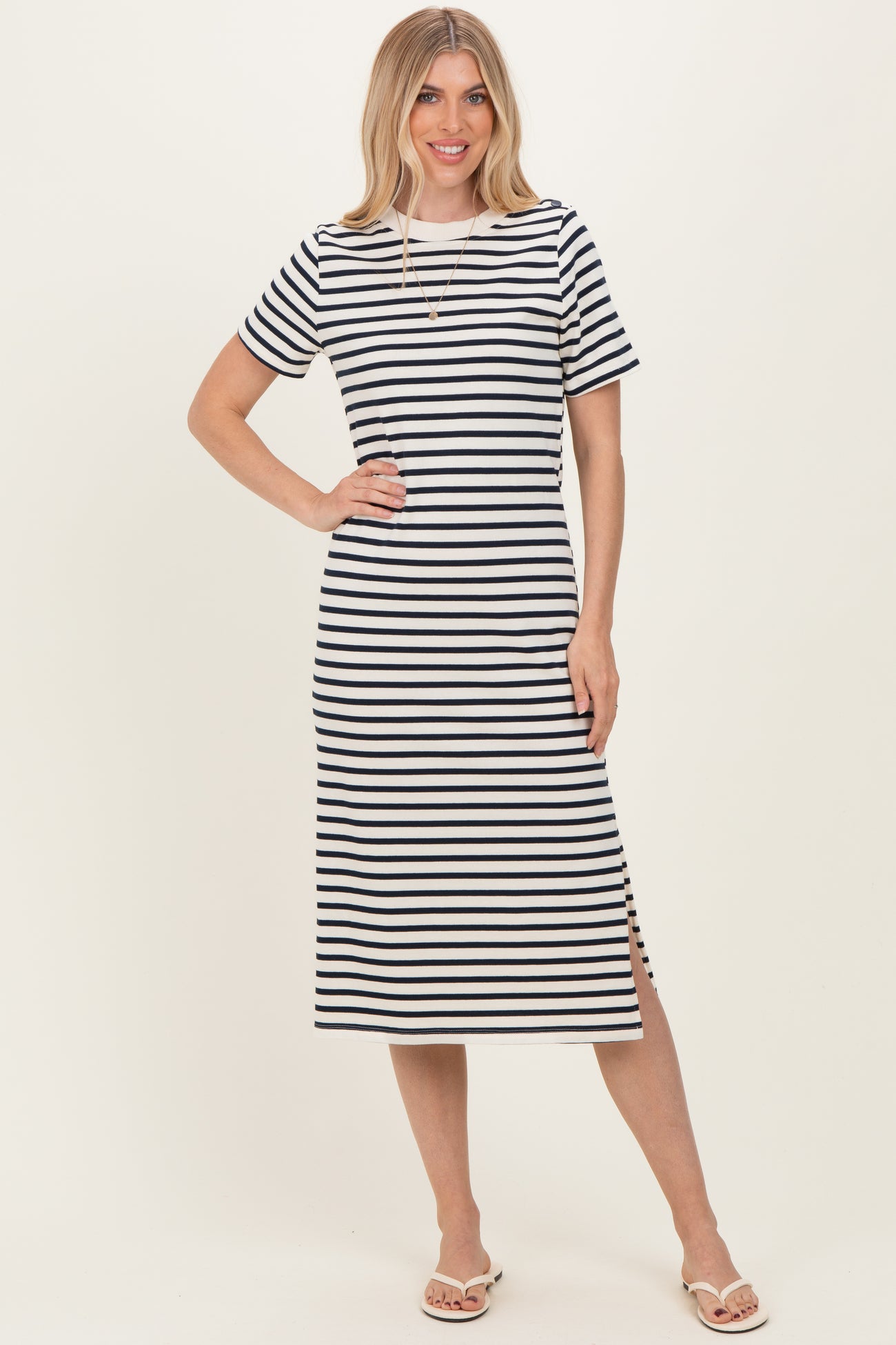 woman wearing a black and white striped midi dress with short sleeves and side slits