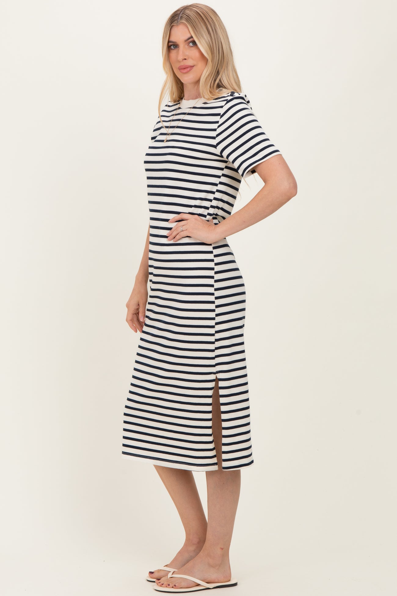 woman wearing a navy and white striped midi dress with short sleeves and side slits