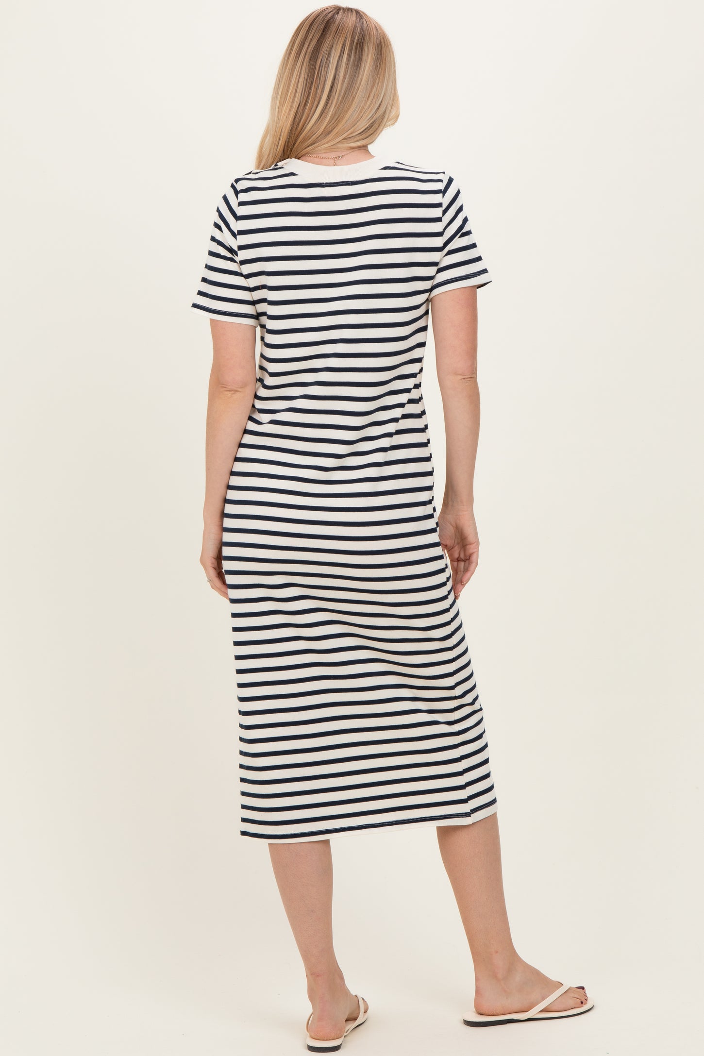 woman wearing a navy and white striped midi dress with short sleeves and a relaxed fit, seen from the back