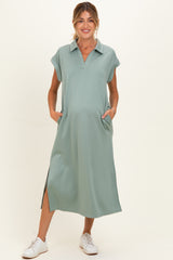 woman wearing a sage green maternity dress with a collared neckline and side pockets, featuring a relaxed fit and slit details