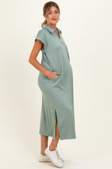 woman wearing a green short sleeve maternity polo dress with pockets and side slits, showcasing her baby bump