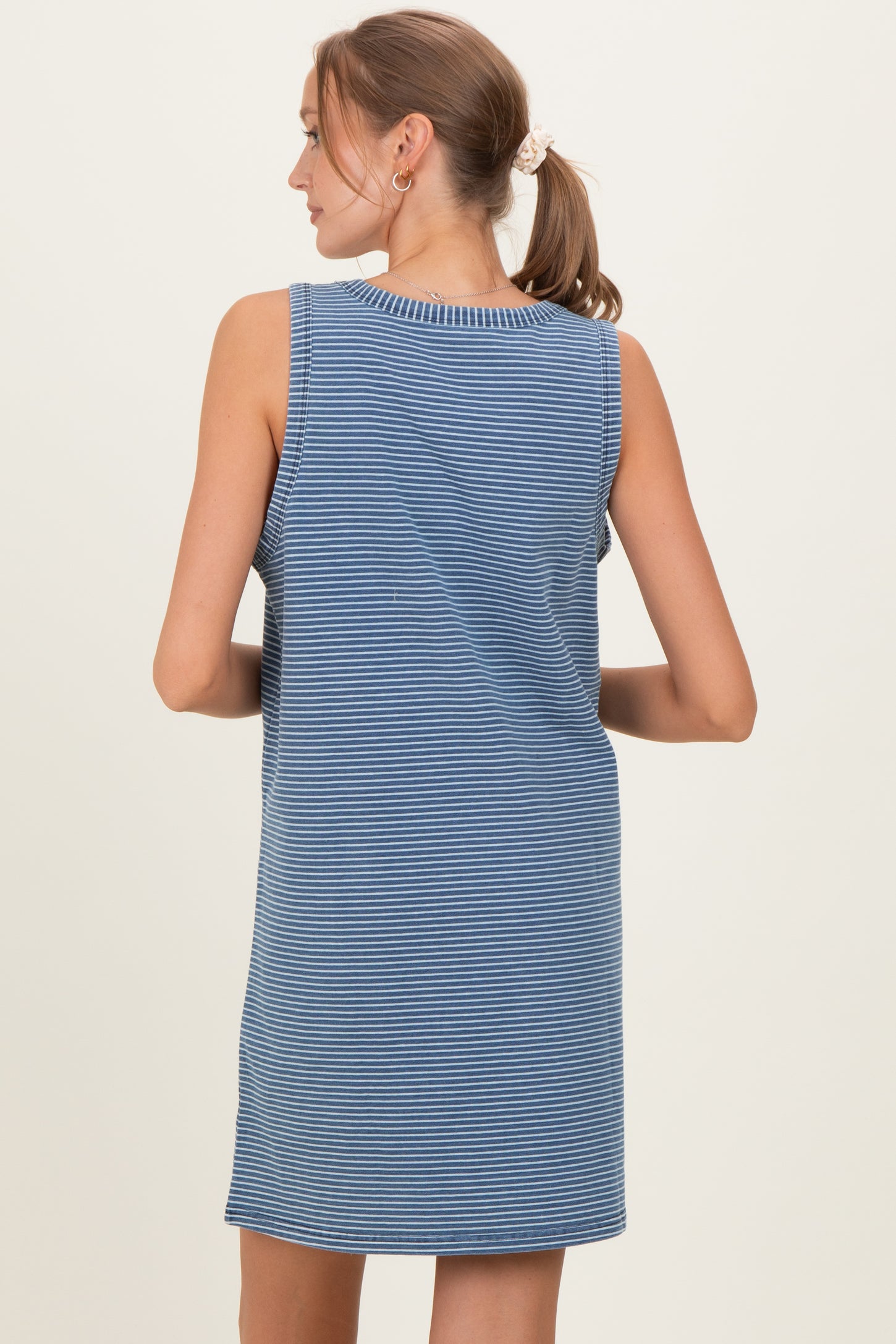 woman wearing a blue striped sleeveless maternity dress, showing the back view