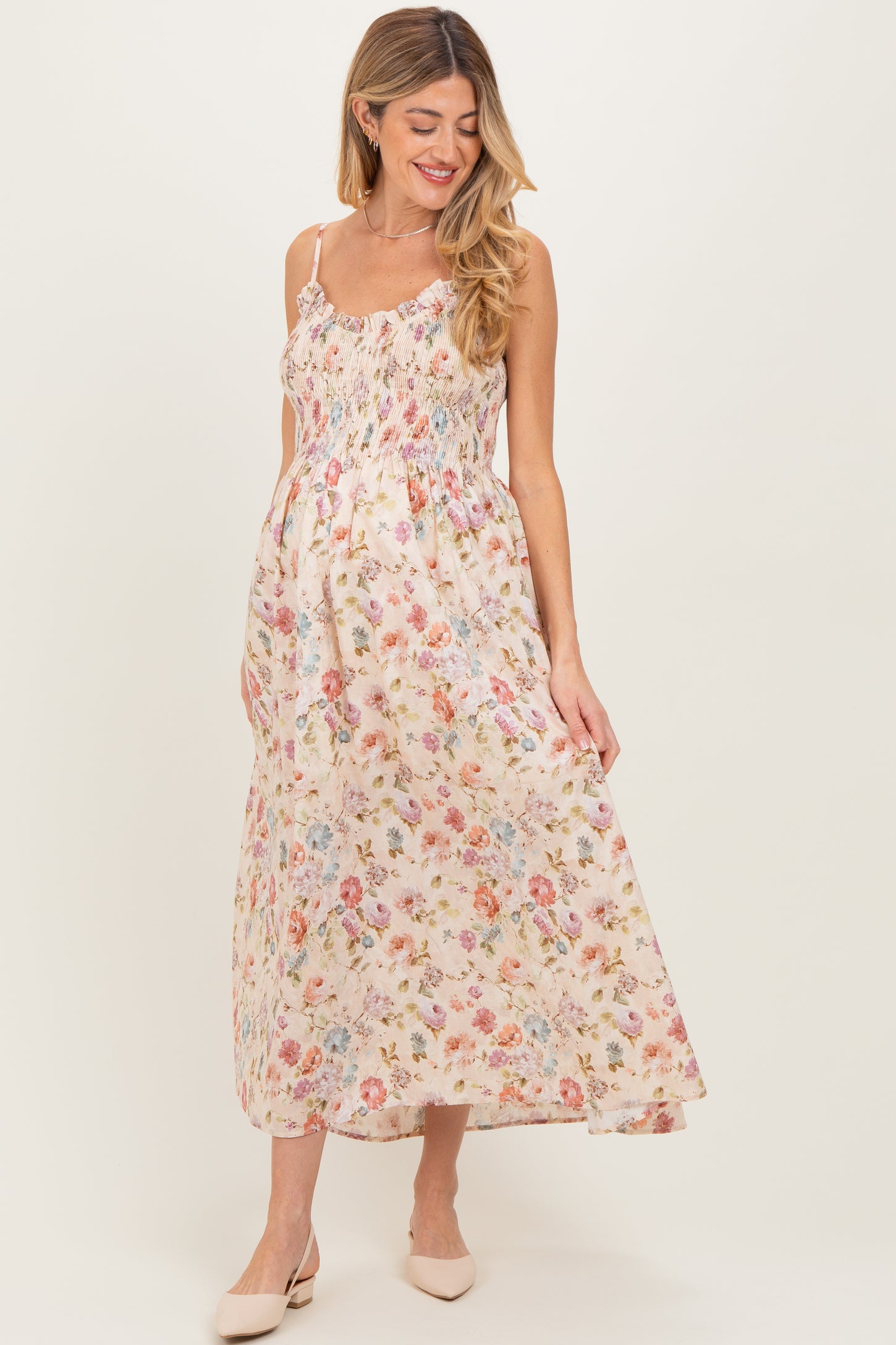 woman wearing a floral maxi maternity dress with smocked bodice and spaghetti straps, showing a baby bump