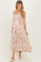 woman wearing a floral maxi maternity dress with smocked bodice and spaghetti straps, showing a baby bump