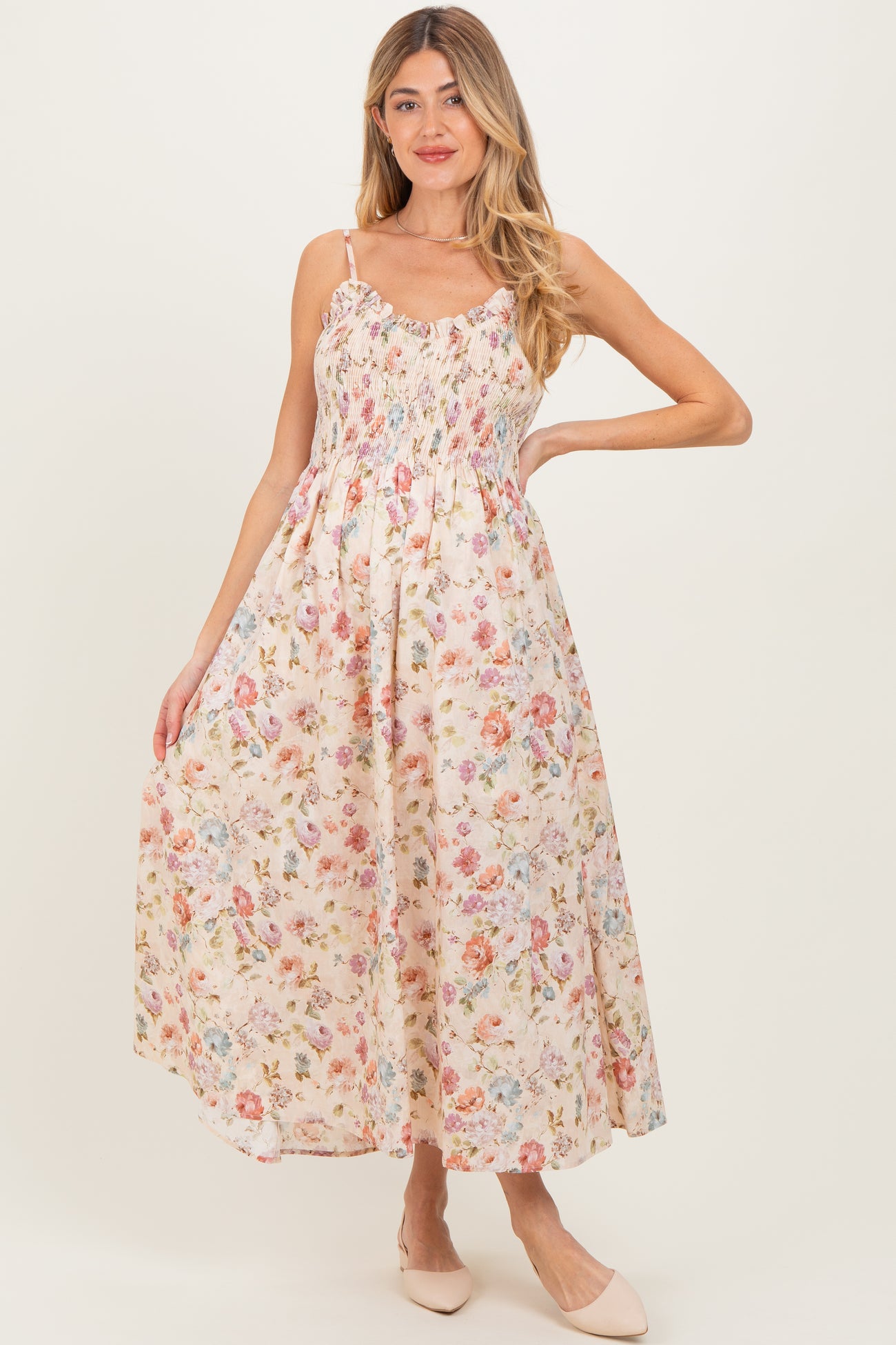 woman wearing a floral print maternity maxi dress with adjustable straps and a smocked bodice, showcasing her baby bump