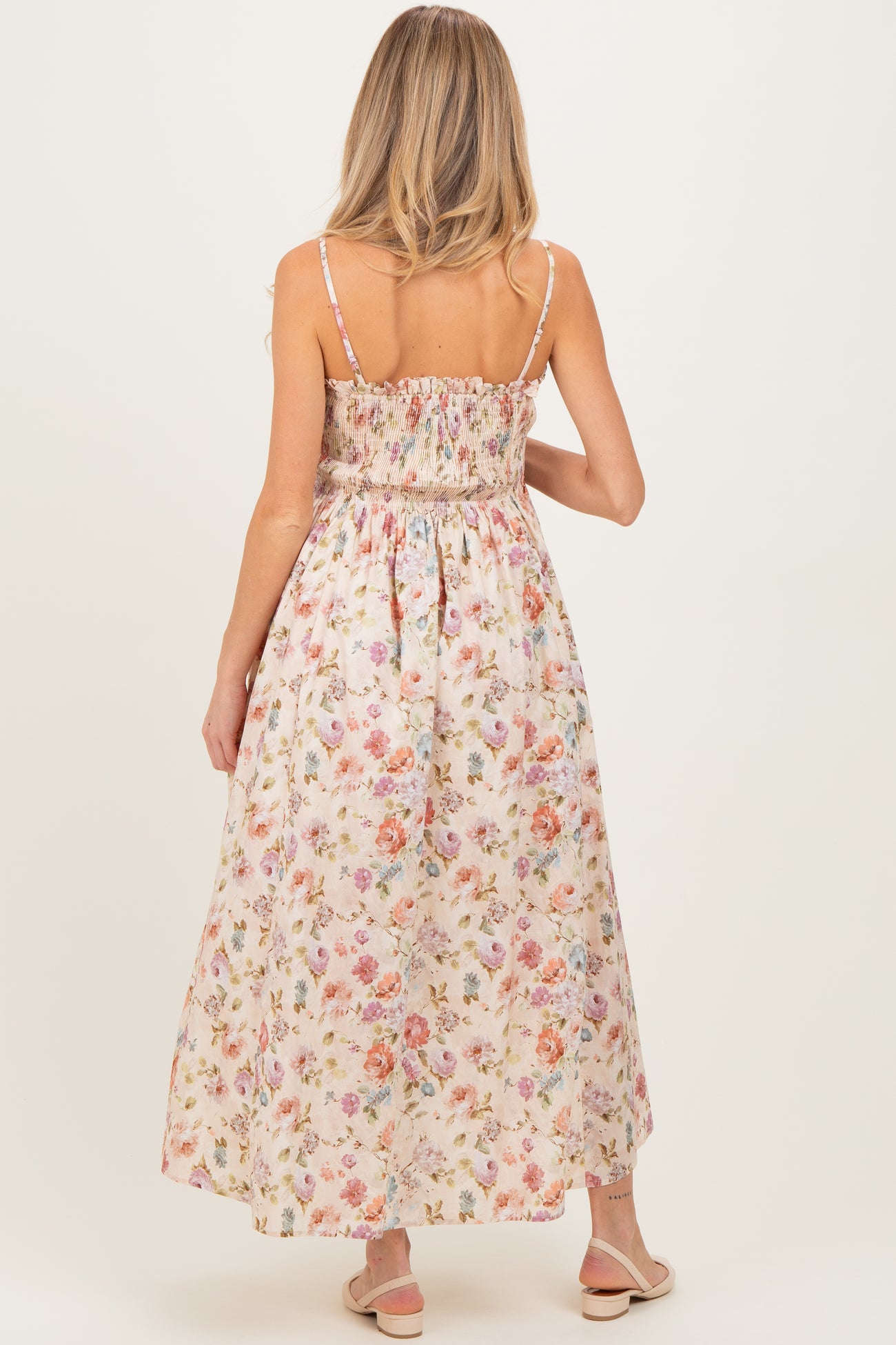 woman wearing a floral maternity maxi dress with smocked bodice and spaghetti straps, showing her back