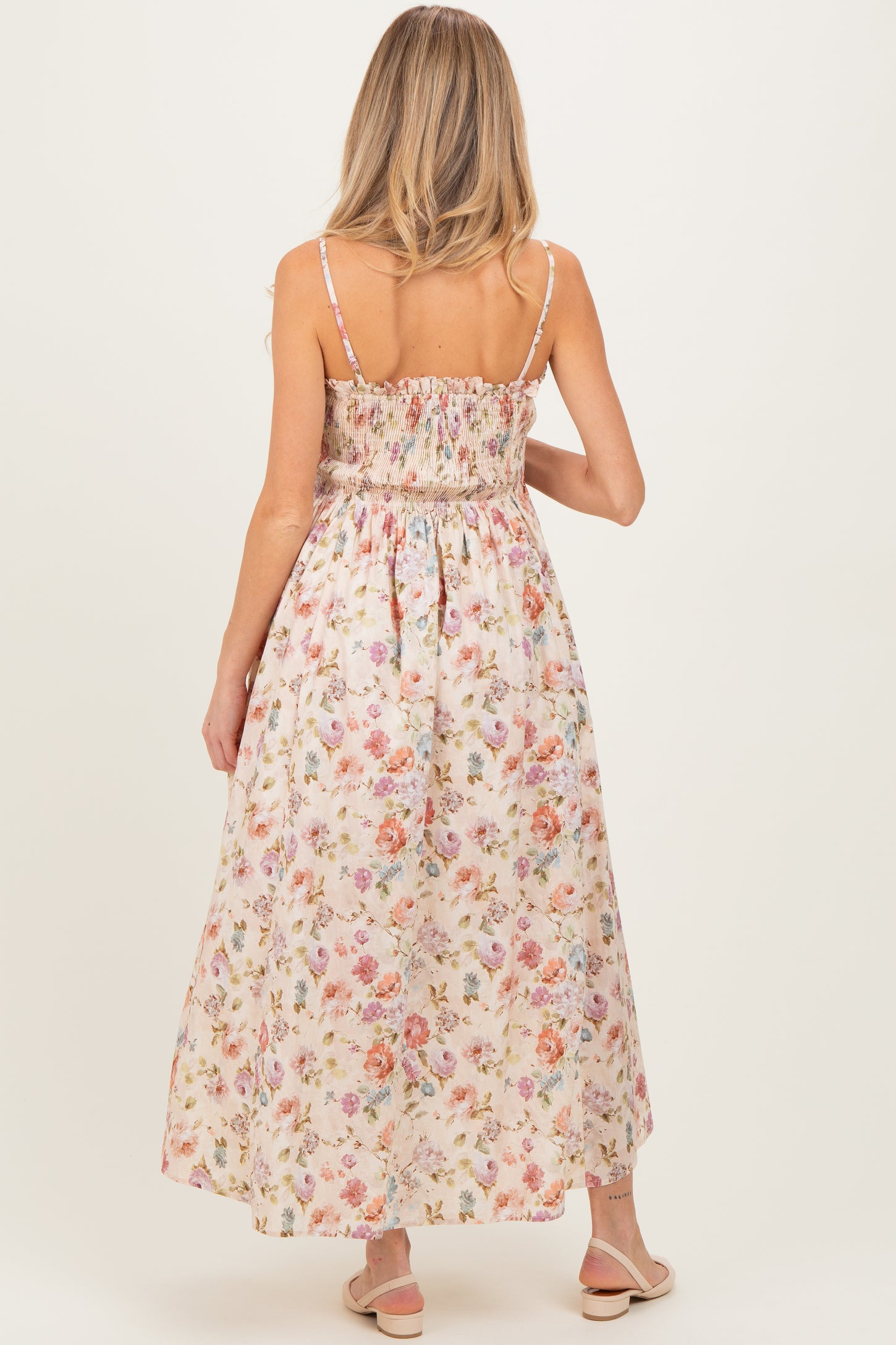 woman wearing a floral maternity maxi dress with smocked bodice and spaghetti straps, showing her back