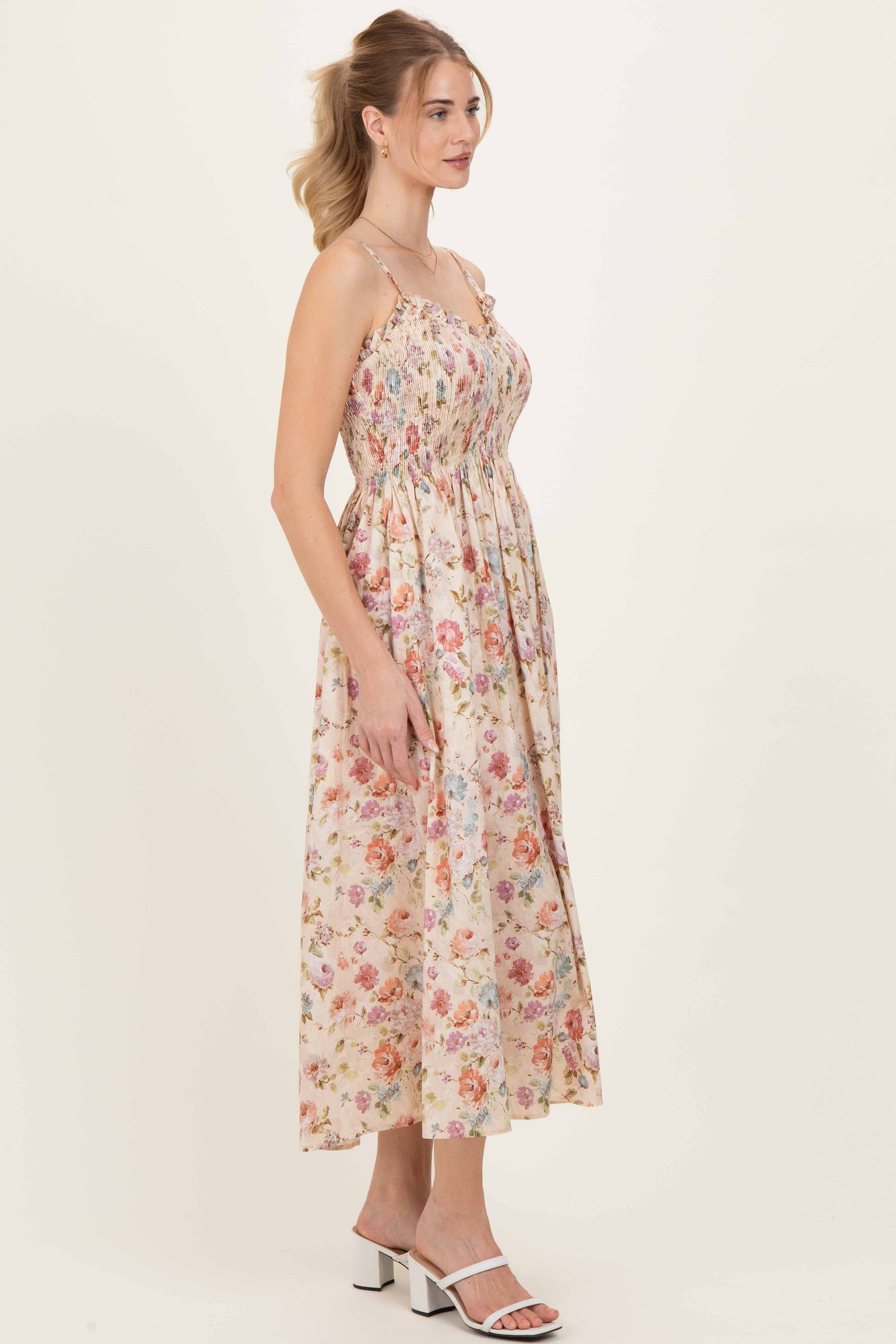 woman wearing a floral printed maxi dress with spaghetti straps and a smocked bodice, standing in profile