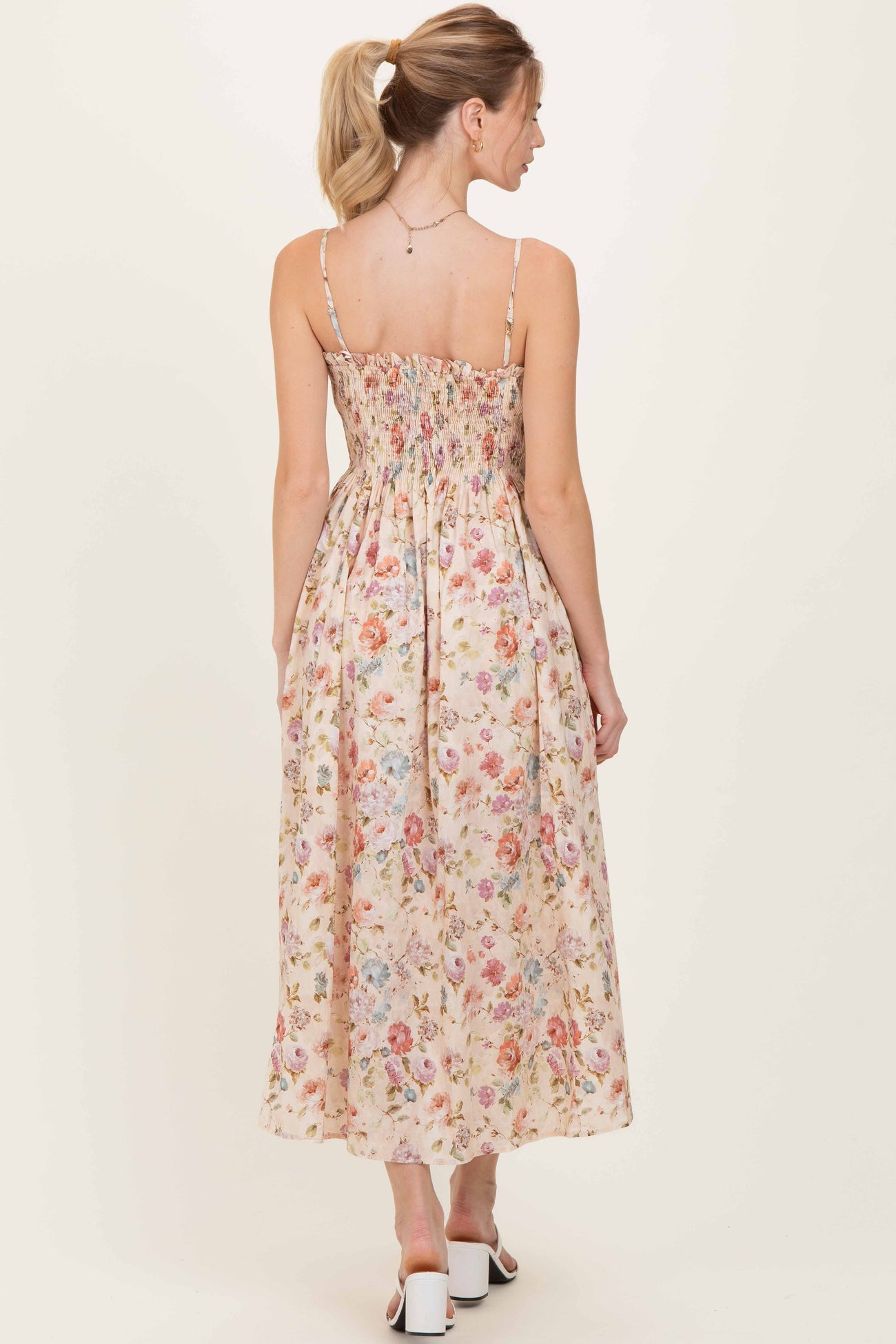 woman wearing a floral midi dress with a smocked bodice and thin straps, seen from the back