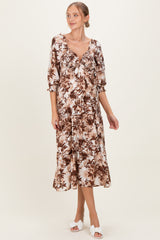 woman wearing a brown floral print maternity dress with a tie front and elbow-length sleeves, showing her baby bump