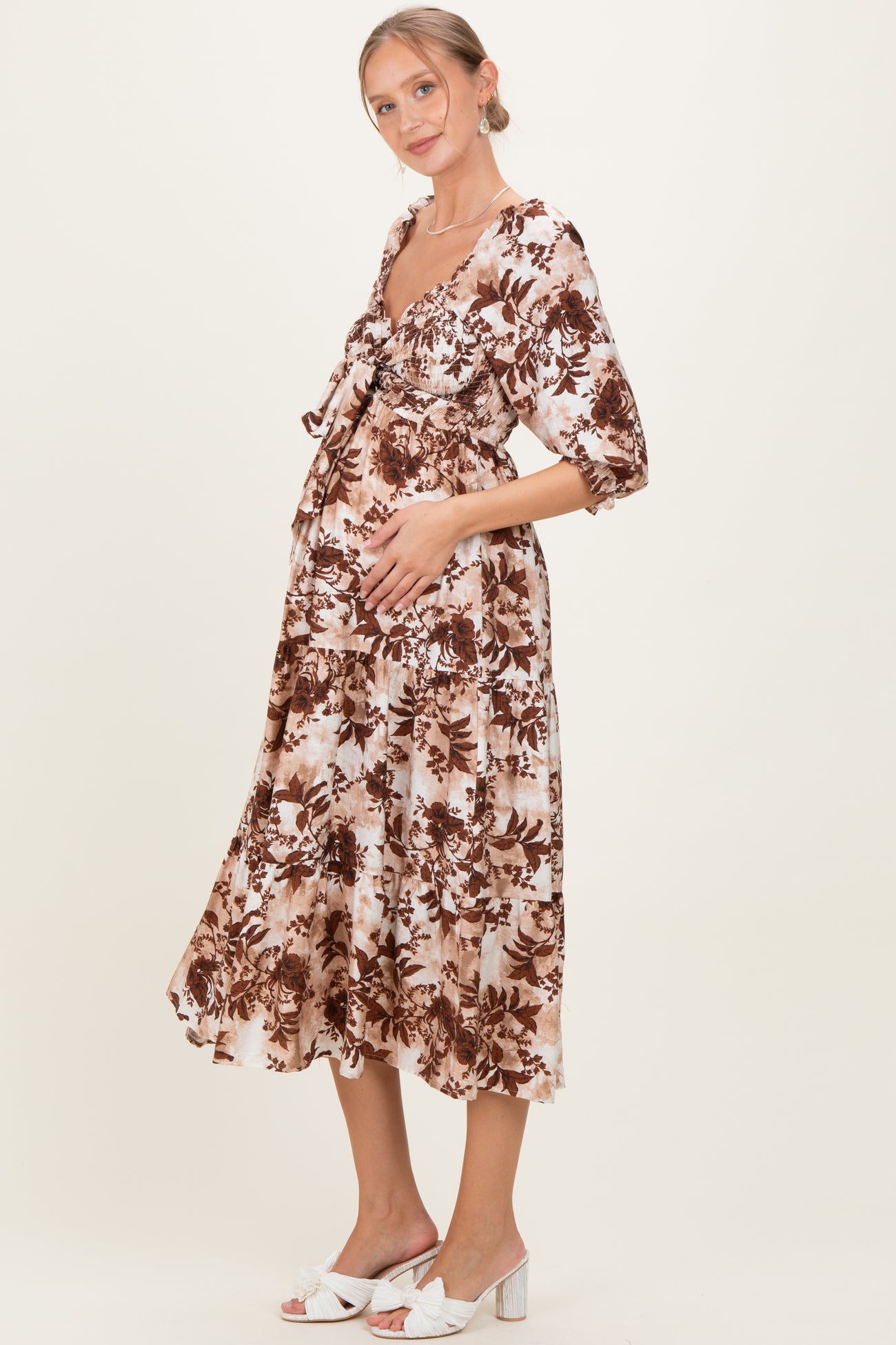 woman wearing a brown and cream floral maternity dress with a baby bump, styled with short puff sleeves and a tiered skirt