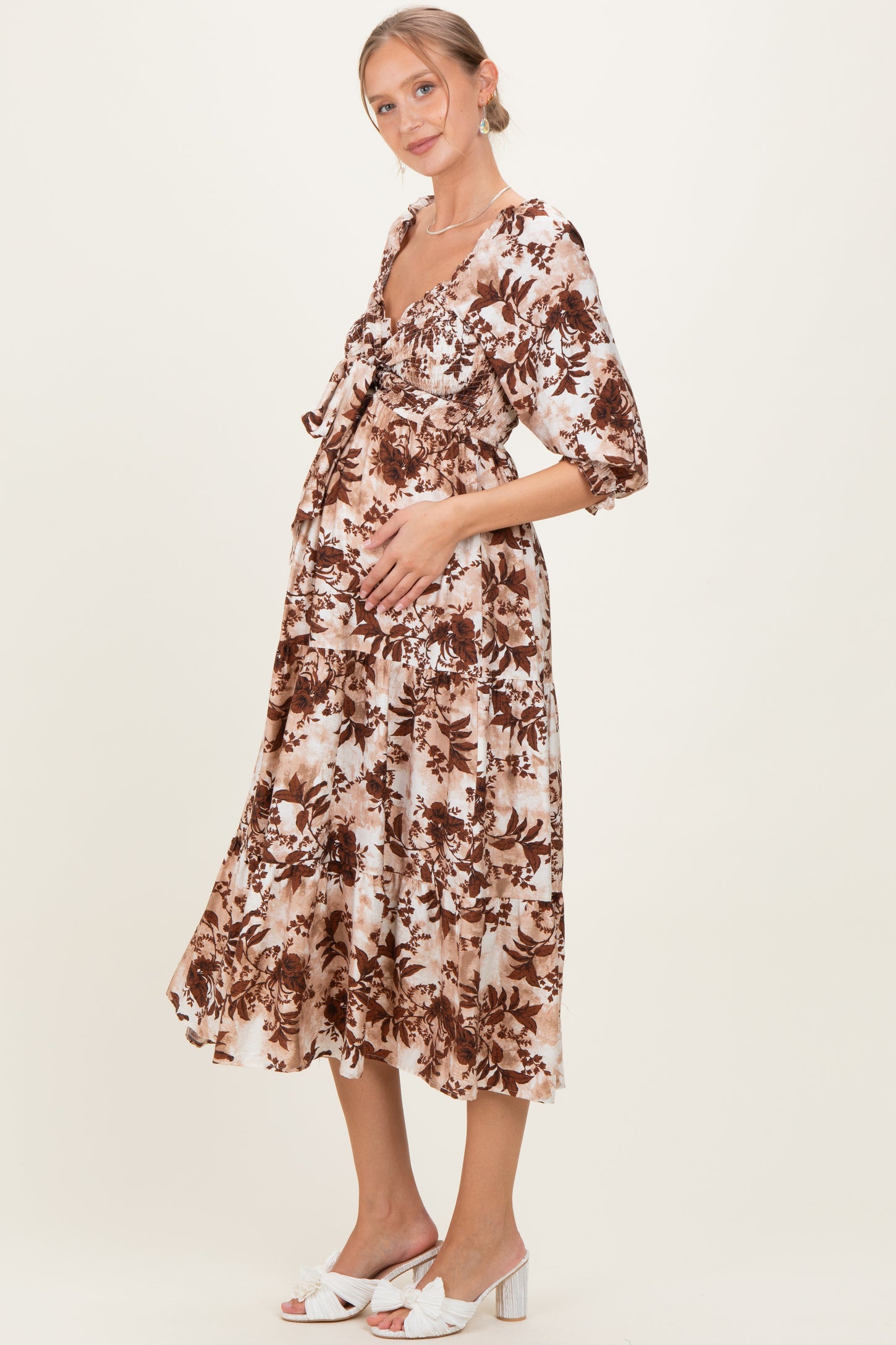 woman wearing a brown and cream floral maternity dress with a baby bump, styled with short puff sleeves and a tiered skirt