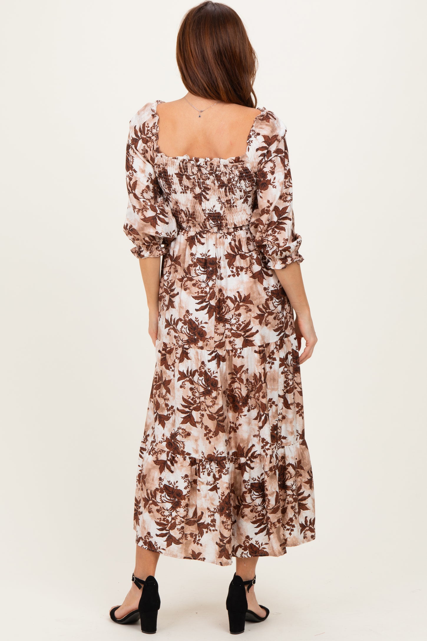 woman wearing a bohemian floral maxi dress with puff sleeves and a smocked back in brown and cream tones