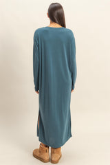 woman wearing a teal long sleeve maxi dress with side slits and brown ankle boots