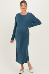 woman wearing a teal long sleeve maternity maxi dress with a pocket and a visible baby bump