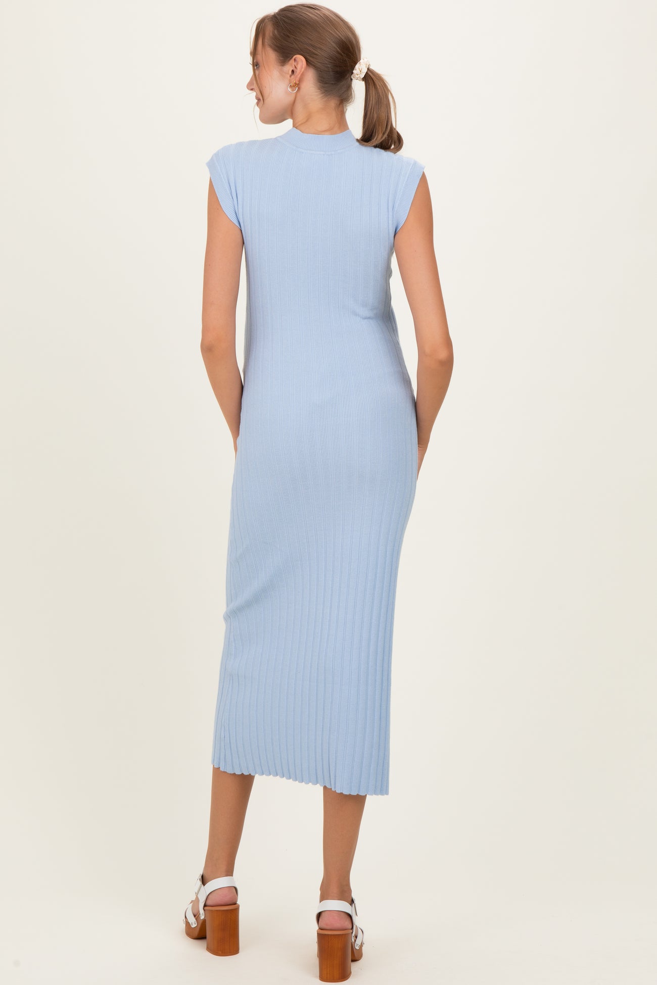 woman wearing a light blue ribbed maternity dress with cap sleeves and a midi length, showing a smooth back silhouette