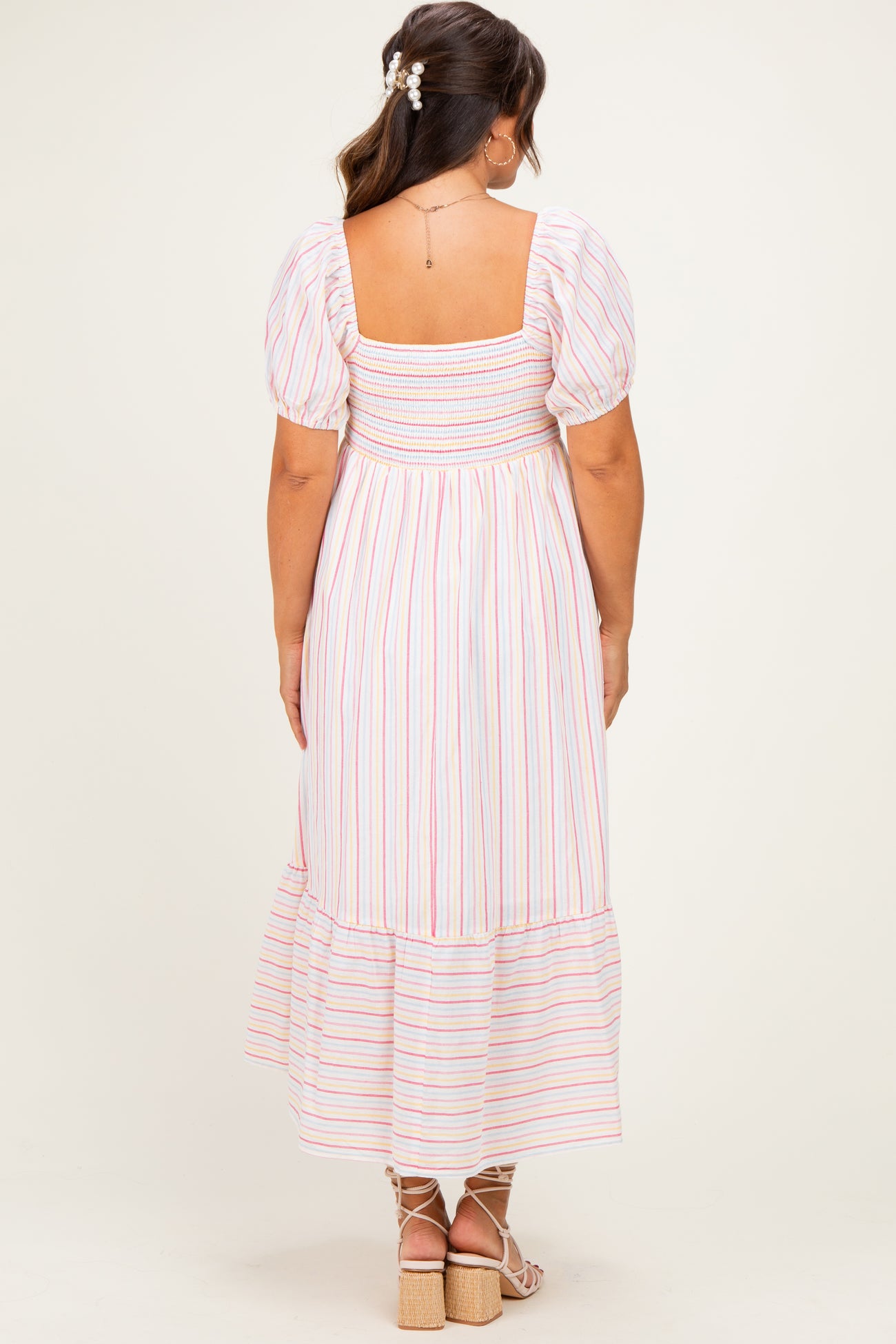 woman wearing a striped maternity maxi dress with puff sleeves and a smocked bodice, showing a baby bump from the back