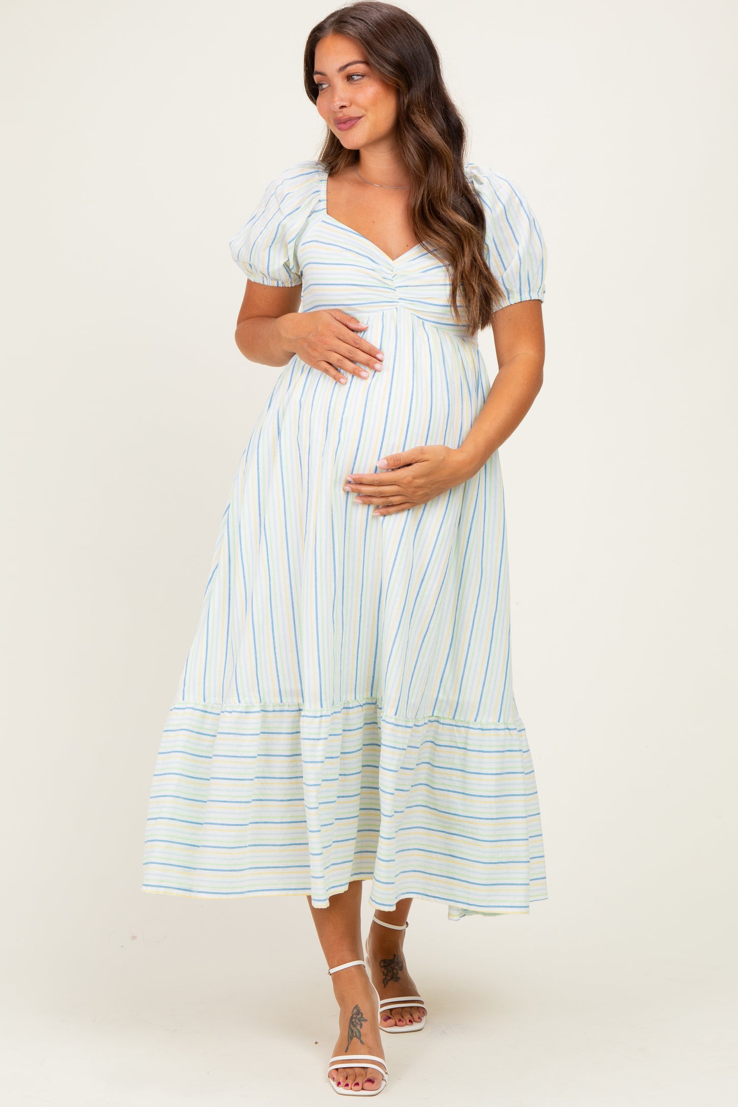 woman wearing a striped maternity maxi dress with puff sleeves and a baby bump